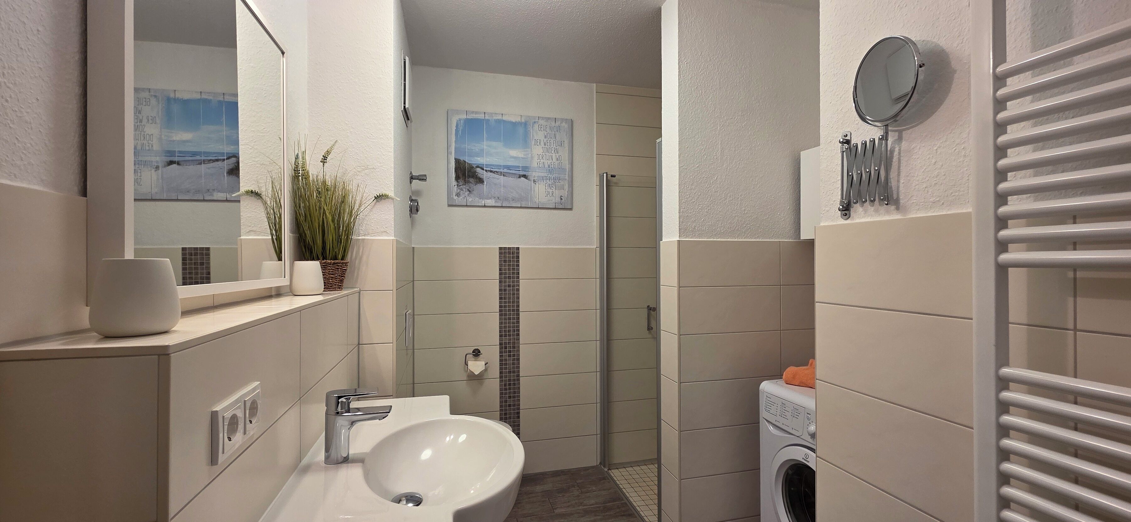 Un baño moderno con lavamanos, espejo y zona de ducha.