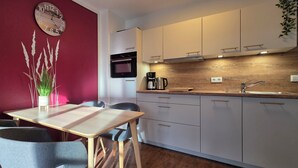 A modern kitchen with a wooden countertop, white cabinets, and a red accent wall. - 2-zi.-fewo im 2. OG, ca. 45 m² für 4 Personen mit Wlan (Graal-Müritz)