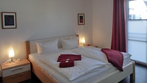 A hotel room with a bed, two bedside tables, a nightstand, a lamp, and two framed pictures on the walls. - 2-zi.-fewo für 4 Personen im 2. OG (Graal-Müritz)