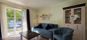 Ein Wohnzimmer mit einer Couch, einem Couchtisch, einer Vitrine und einer Stehlampe.