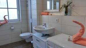 A modern bathroom with a toilet, sink, and washing machine. - 2-zi.-fewo für 4 Personen im 1. OG mit Wlan (Graal-Müritz)