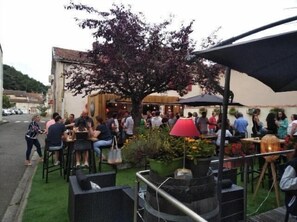 An outdoor seating area with tables and chairs, surrounded by greenery and a building in the background. - Chez l'ahumat (Aire-sur-l'Adour)