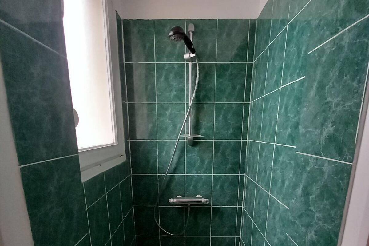 A small, enclosed shower area with a built-in seat and a handheld showerhead.