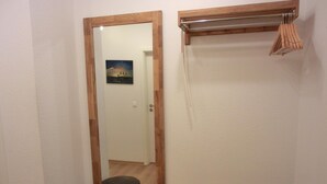 A bathroom with a wooden-framed mirror, a small stool, and a metal drying rack.