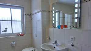 A bathroom with a toilet, sink, and window.