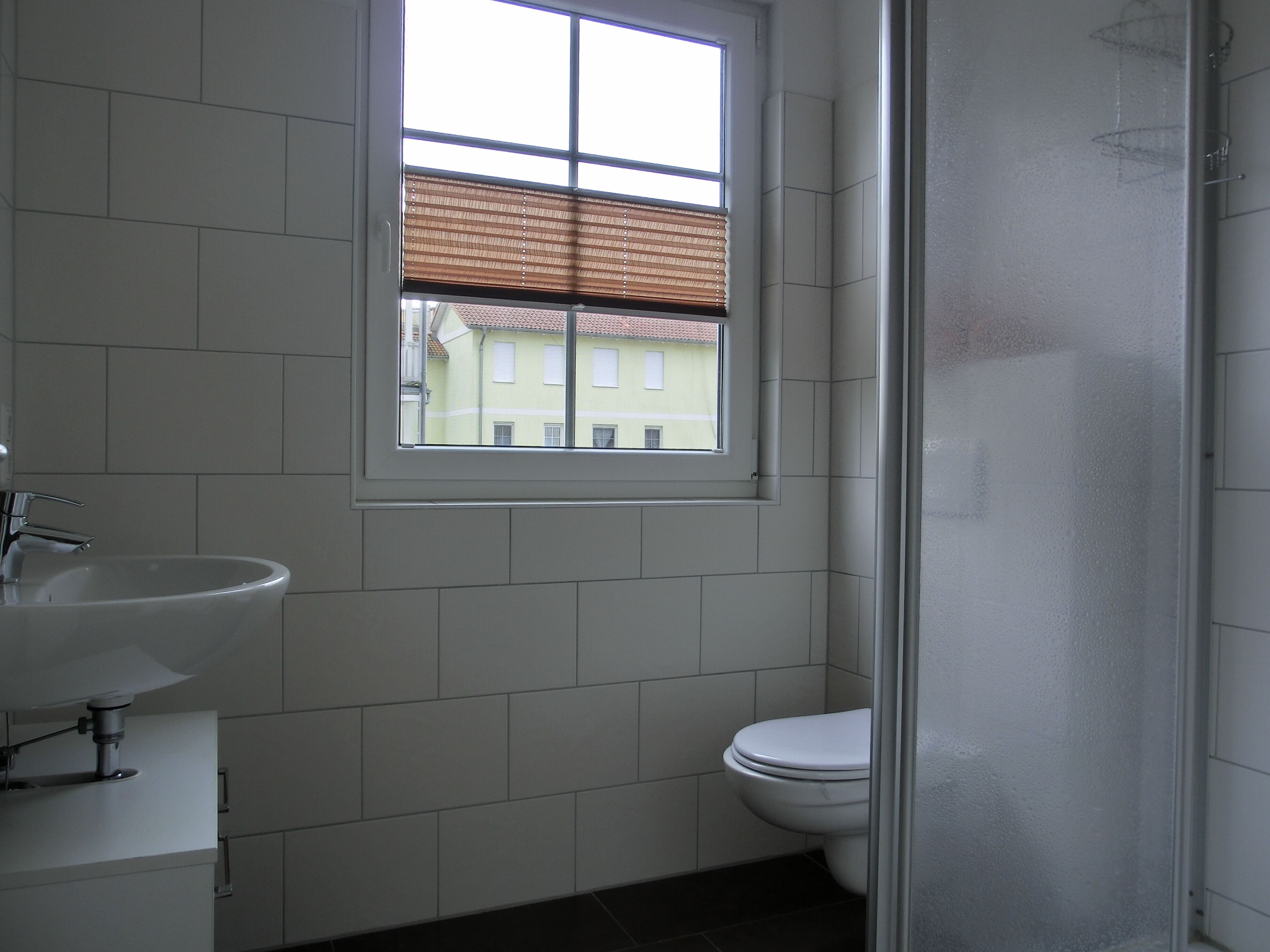 Ein Badezimmer mit Fenster, Waschbecken und Toilette.
