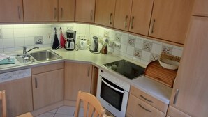 A kitchen with wooden cabinets, a Bosch dishwasher, a Bosch oven, a sink, a toaster, a kettle, and a coffee maker. - 3-zi.-fewo in Angenehmer und Ruhiger Lage im Erdgeschoss für 6 Pers (Graal-Müritz)