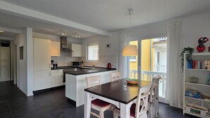 Eine moderne Küche mit weißen Schränken, einer zentralen Kochinsel und einem Essbereich mit Tisch und Stühlen.