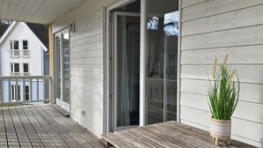 Eine Holzterrasse mit einer Bank, einem Blumentopf und einer Schiebetür zum Balkon.