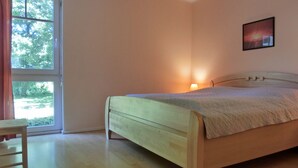 A bedroom with a bed, a chair, a window, and a wall-mounted picture. - Strandnahe 3-zimmer-fewo im EG für 4 Personen (Graal-Müritz)