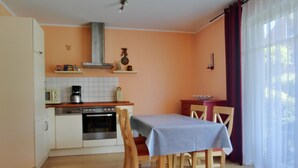 A compact kitchen with a dining area, featuring a stove, microwave, and oven. - Strandnahe 3-zimmer-fewo im EG für 4 Personen (Graal-Müritz)