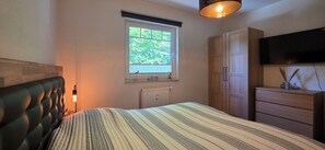 A bedroom with a bed, a window, a radiator, a wardrobe, a dresser, and a television. - 2-room apartment for max. 2 pers. with balcony on the 1st floor (Graal-Müritz)