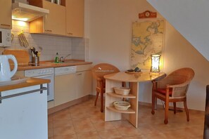 Une cuisine compacte avec un coin repas, comprenant une cuisinière, un évier et une carte accrochée au mur.