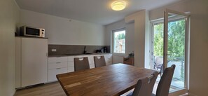 Una cucina moderna con microonde, lavello e macchina da caffè. È presente un tavolo da pranzo con sedie e vista sull'esterno tramite una porta scorrevole in vetro.