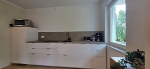 Una cucina compatta con forno a microonde integrato, lavello e macchina da caffè.