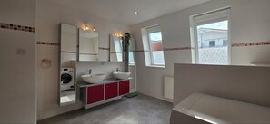 Un bagno con lavatrice, due lavandini, uno specchio e una finestra.