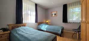 A room with two beds, a desk, a chair, a lamp, and a framed picture on the wall. - 3-room apartment on the 1st floor, suitable for 6 people.   (Graal-Müritz)