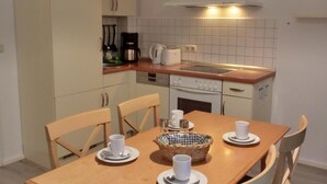A small kitchen with a dining table set for four, a coffee maker, and a toaster. - 3-room apartment on the first floor, suitable for 6 people. (Graal-Müritz)