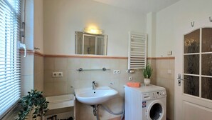 A bathroom with a sink, mirror, towel rack, and a washing machine. - 3-room apartment on the first floor, suitable for 6 people. (Graal-Müritz)