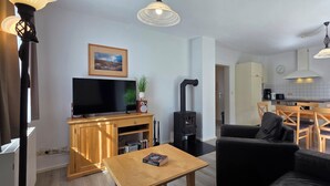 A modern living room with a flat-screen TV, a sofa, a wooden coffee table, and a fireplace. - 3-room apartment on the first floor, suitable for 6 people. (Graal-Müritz)