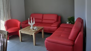 Una sala de estar moderna con un sofá rojo, una mesa de centro de madera y un sillón rojo.