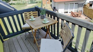 A wooden deck with a table and chairs, a potted plant, and a view of a residential area. - 2- Zi.-fewo für 2 Personen mit Balkon und Wlan (Graal-Müritz)