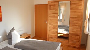 Ein Schlafzimmer mit einem Bett, einem Nachttisch und einem Kleiderschrank mit Spiegel.