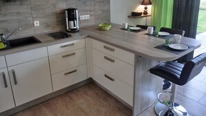 Eine moderne Küche mit Einbauherd, Kaffeemaschine und Essbereich mit Tisch und Stühlen.
