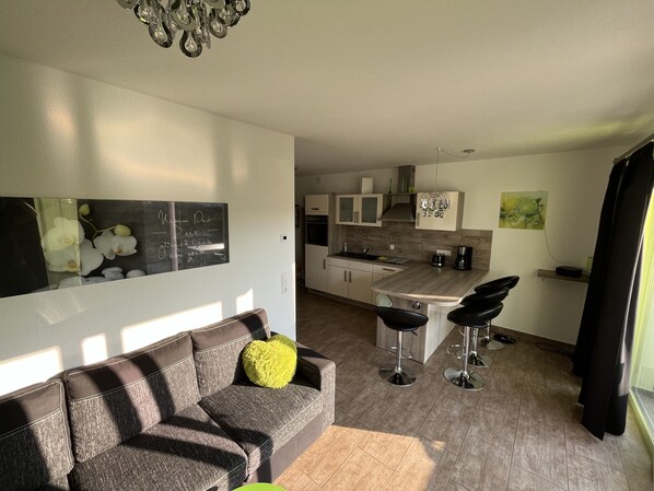 A modern kitchen with a central island, bar stools, and a dining area.