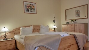 A neatly arranged bedroom with a bed, two bedside tables with lamps, a dresser, and a wall-mounted mirror. - 3-zimmer-appartement im 1. OG mit Wlan (Graal-Müritz)