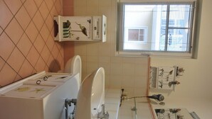 A bathroom with a toilet, bidet, and a window with blinds. - 3-zimmer-appartement im 1. OG mit Wlan (Graal-Müritz)