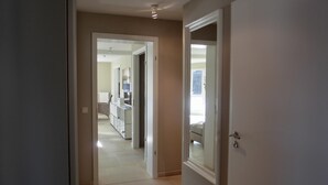 Ein Flur, der zu einem Schlafzimmer mit großem Fenster, Schreibtisch und Stuhl führt.