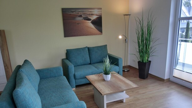 Un salon avec un canapé d’angle, une table basse et une plante en pot.
