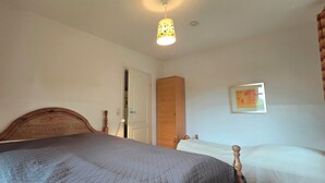 Een slaapkamer met een bed, een kledingkast, een deur en een aan de muur hangend schilderij.