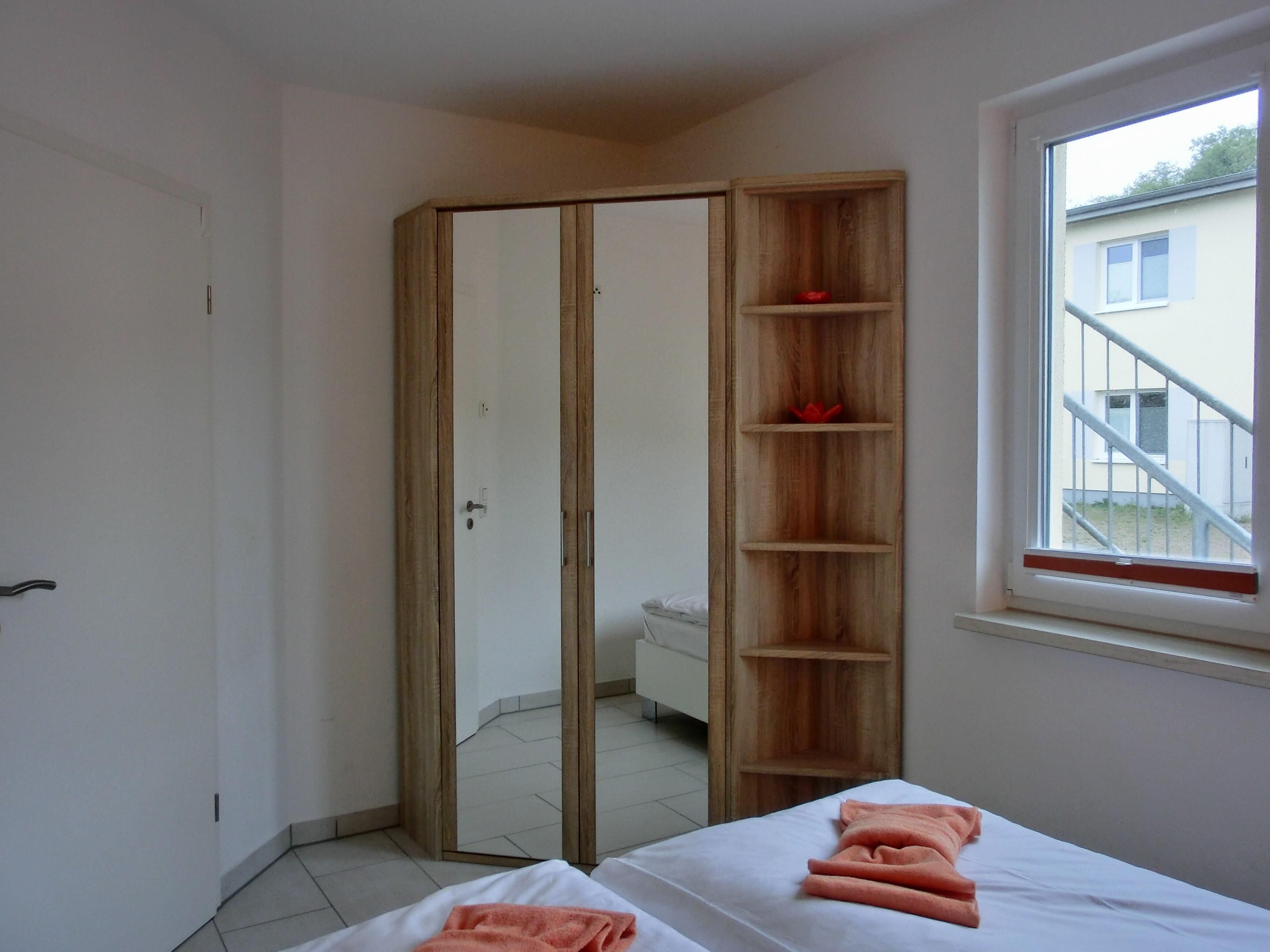 Une chambre avec un placard, un lit avec des serviettes et une fenêtre donnant sur un bâtiment à l’extérieur.