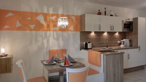 Une cuisine moderne dotée d’un îlot central, de meubles blancs et d’un four à micro-ondes.