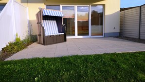 Un espace patio doté d’un coin salon intégré, d’une porte-fenêtre coulissante et d’une pelouse bien entretenue.