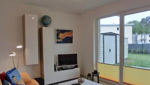 Un salon moderne avec un canapé, une table basse, un téléviseur à écran plat, un globe terrestre et un tableau accroché au mur.