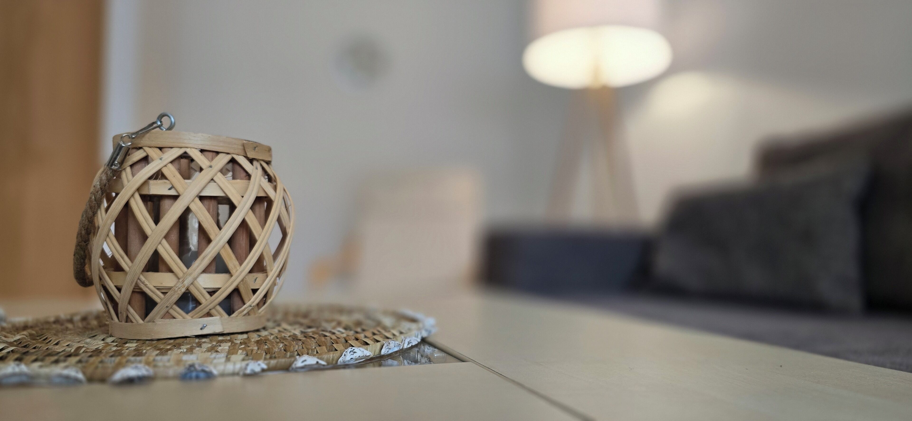 A woven candle holder on a woven placemat.