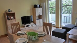 Un coin repas avec une table dressée pour quatre personnes, un téléviseur et un meuble avec des étagères.