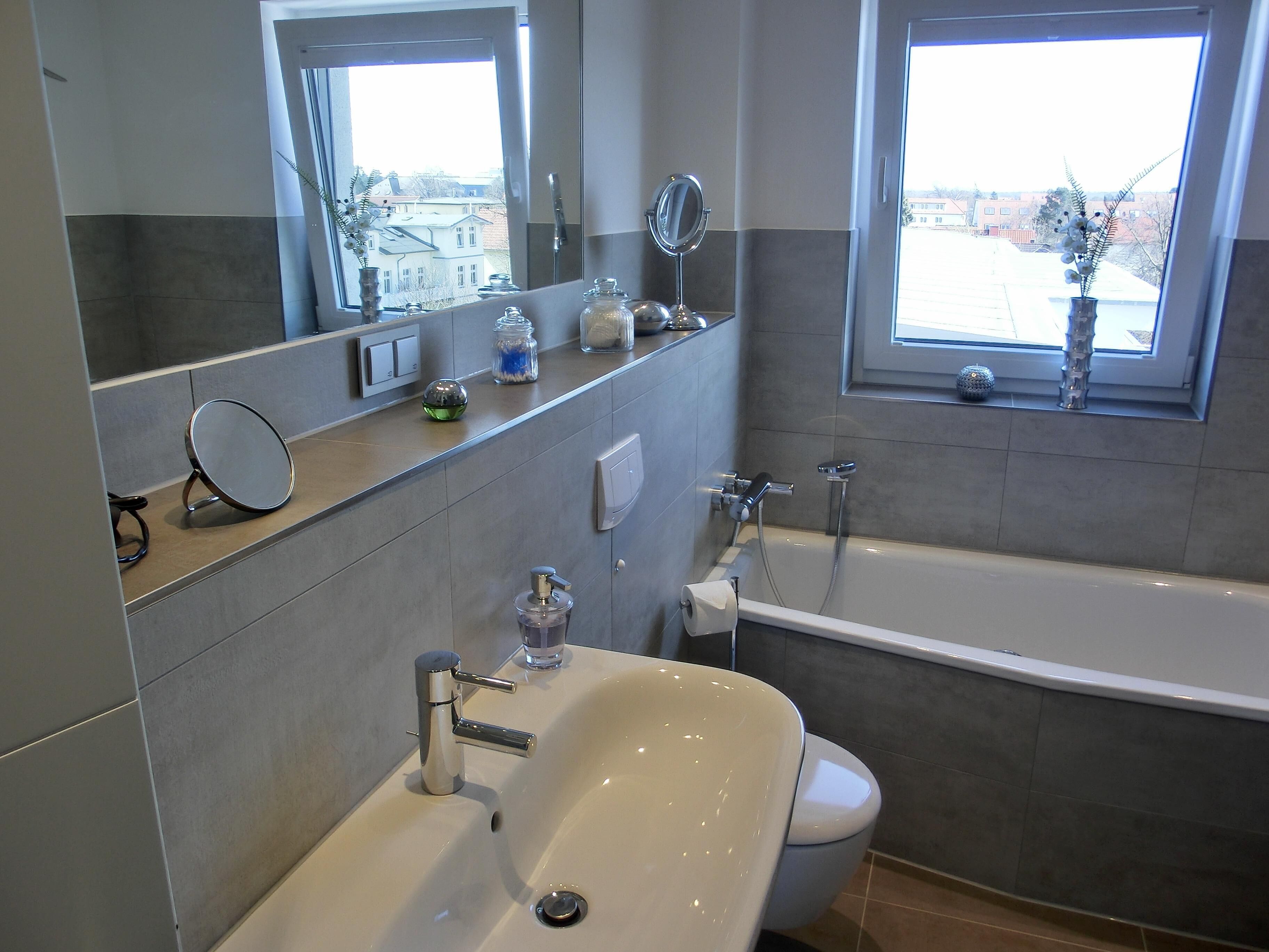 Un baño moderno con bañera, lavabo, espejo y ventana con vistas al exterior.