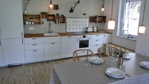 A modern kitchen with white cabinets, wooden countertops, and a dining area set for four. - Strandnahe 3-zimmer-ferienwohnung für 4 Pers. mit Terrasse (Graal-Müritz)