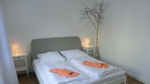 A neatly made bed with white linens and two orange towels folded at the foot. - Strandnahe 3-zimmer-ferienwohnung für 4 Pers. mit Terrasse (Graal-Müritz)