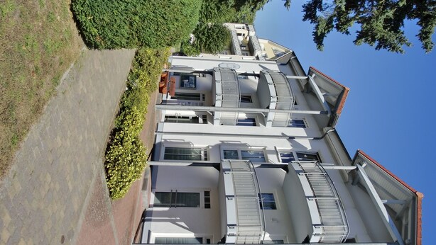 A multi-story building with a symmetrical facade, large windows, and a flat roof. - Strandnahe 2-zi.-fewo mit Balkon für 3 Personen in Ruhiger Lage (Graal-Müritz)