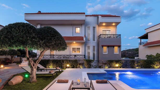 Un bâtiment moderne à deux étages doté d’une piscine, d’un espace extérieur aménagé et d’un patio bien éclairé.