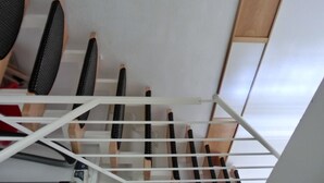 Estante metálico blanco con varios ganchos negros y de madera, probablemente para colgar objetos.