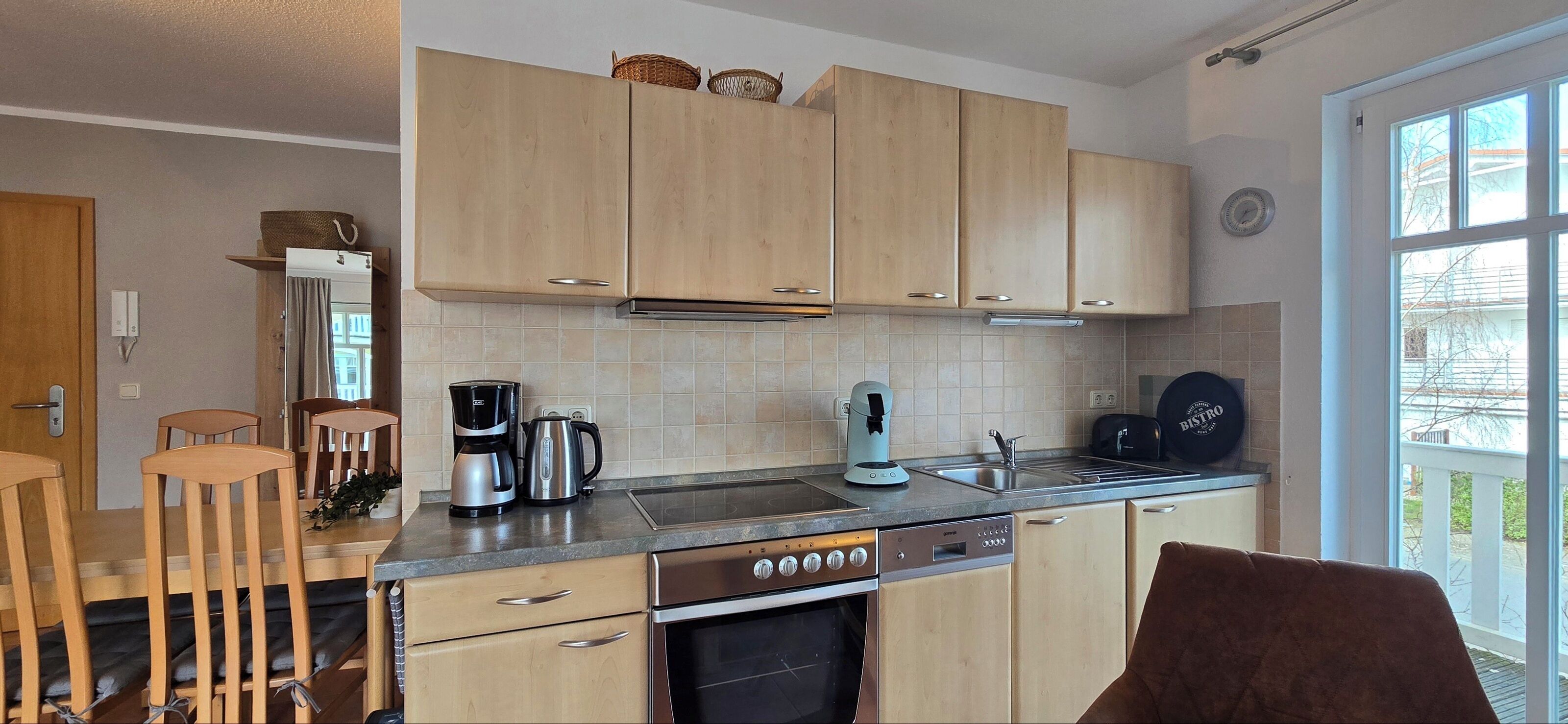 A modern kitchen with wooden cabinets, a dishwasher, a coffee maker, and a sink.