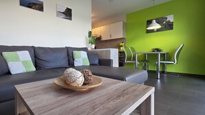En moderne stue med en grå sofa, et træbord og en grøn accentvæg.