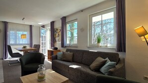Ein modernes Wohnzimmer mit einer Couch, einem Couchtisch und einem Essbereich mit Tisch und Stühlen.