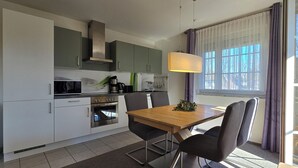 Eine moderne Küche mit Essbereich, ausgestattet mit einem Holztisch, Stühlen und einer Pendelleuchte.